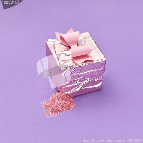 Image of A ripped gift box with colorful candy on a purple background.