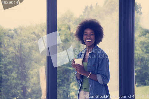 Image of African American woman drinking coffee looking out the window