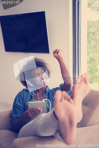 Image of African american woman at home in chair with tablet and head pho