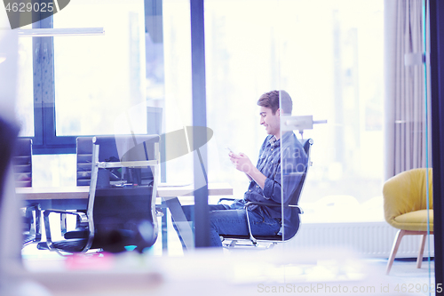 Image of Young casual businessman using smartphone