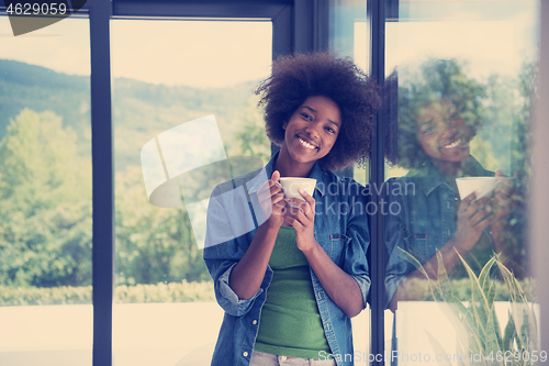 Image of African American woman drinking coffee looking out the window