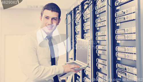 Image of businessman with laptop in network server room