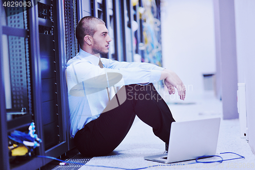 Image of businessman with laptop in network server room