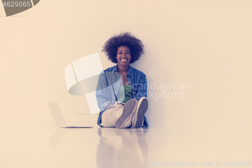 Image of african american woman sitting on floor with laptop