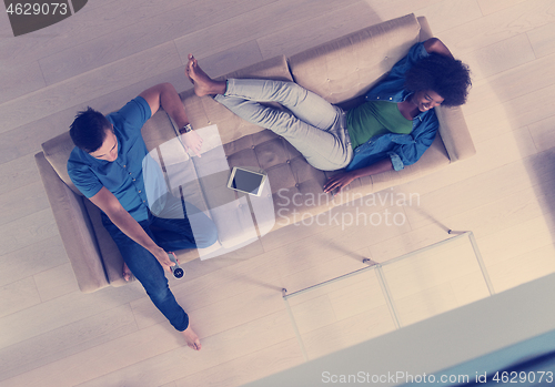 Image of multiethnic couple relaxes in the living room top view