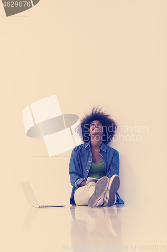 Image of african american woman sitting on floor with laptop