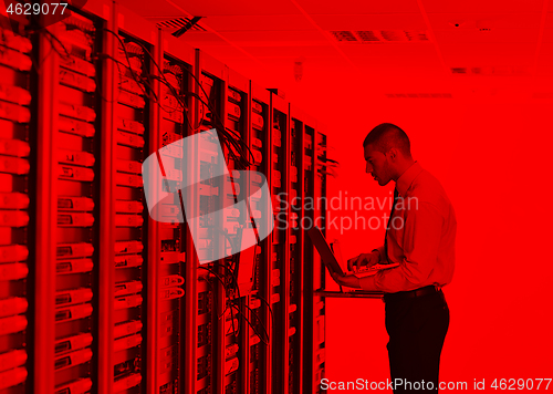 Image of businessman with laptop in network server room