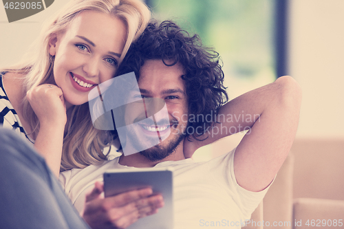 Image of couple relaxing at  home with tablet computers