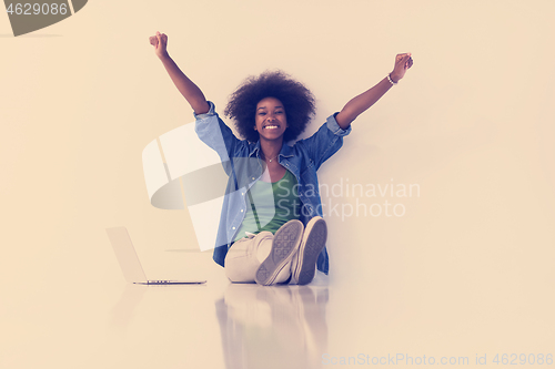 Image of african american woman sitting on floor with laptop