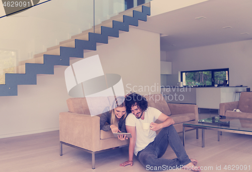 Image of couple relaxing at  home with tablet computers