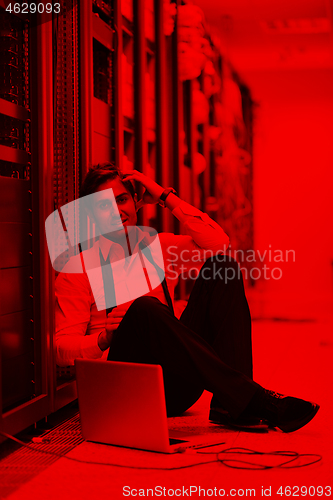 Image of businessman with laptop in network server room