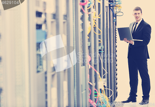 Image of businessman with laptop in network server room