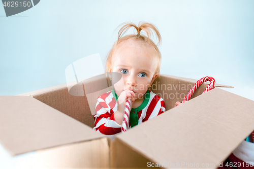 Image of Cute baby girl 1 year old sitting at box over Christmas background. Holiday season.