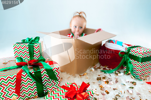 Image of Cute baby girl 1 year old sitting at box over Christmas background. Holiday season.