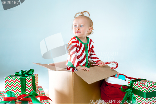 Image of Cute baby girl 1 year old sitting at box over Christmas background. Holiday season.