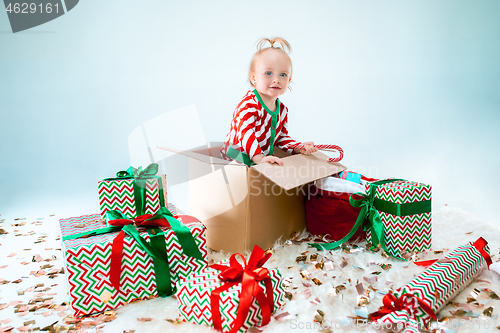 Image of Cute baby girl 1 year old sitting at box over Christmas background. Holiday season.