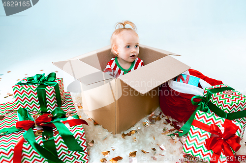 Image of Cute baby girl 1 year old sitting at box over Christmas background. Holiday season.