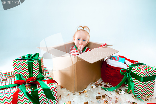 Image of Cute baby girl 1 year old sitting at box over Christmas background. Holiday season.