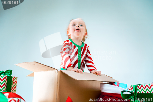 Image of Cute baby girl 1 year old sitting at box over Christmas background. Holiday season.