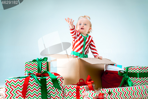 Image of Cute baby girl 1 year old sitting at box over Christmas background. Holiday season.
