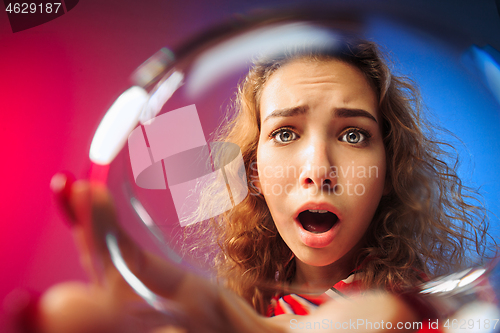 Image of The surprised young woman in party clothes posing with glass of wine.