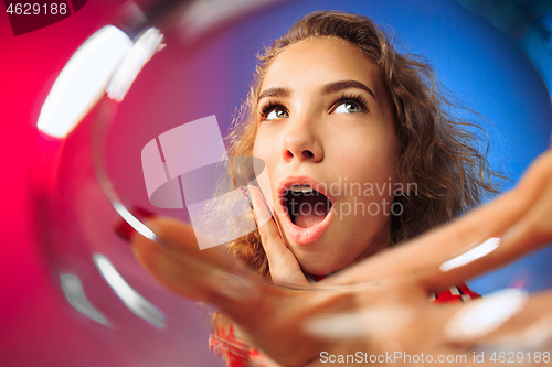 Image of The surprised young woman in party clothes posing with glass of wine.