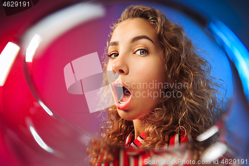 Image of The surprised young woman in party clothes posing with glass of wine.