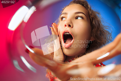 Image of The surprised young woman in party clothes posing with glass of wine.