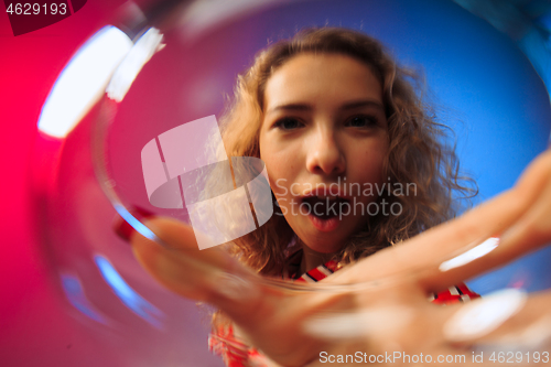 Image of The surprised young woman in party clothes posing with glass of wine.