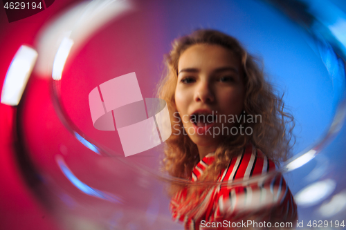 Image of The surprised young woman in party clothes posing with glass of wine.