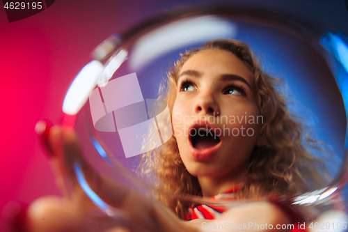 Image of The surprised young woman in party clothes posing with glass of wine.