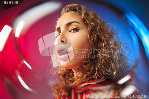 Image of The surprised young woman in party clothes posing with glass of wine.