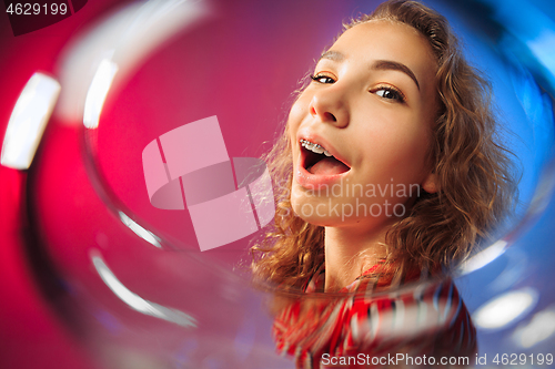 Image of The surprised young woman in party clothes posing with glass of wine.