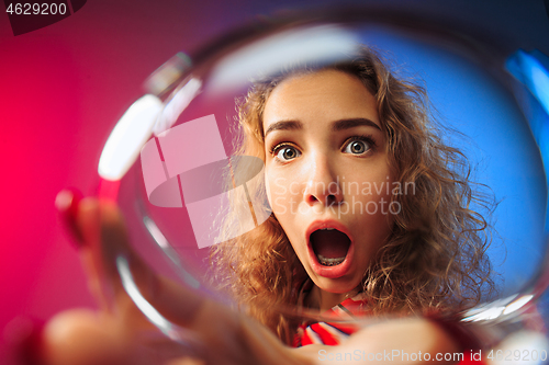 Image of The surprised young woman in party clothes posing with glass of wine.