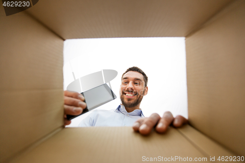 Image of smiling man taking smartphone out parcel box