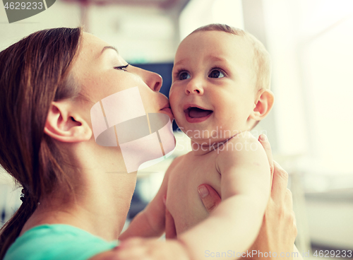 Image of happy young mother kissing little baby at home