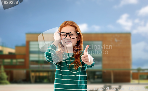 Image of red haired student girl in glasses over school