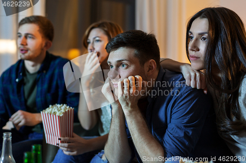 Image of friends with beer and popcorn watching tv at home