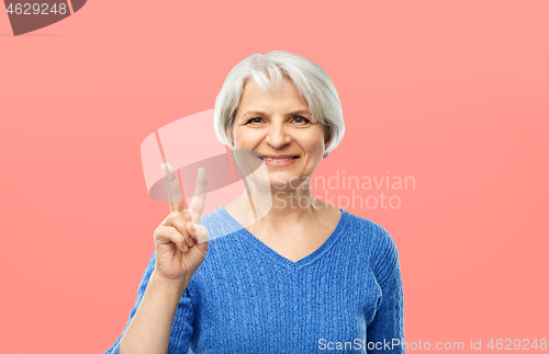 Image of portrait of smiling senior woman showing peace