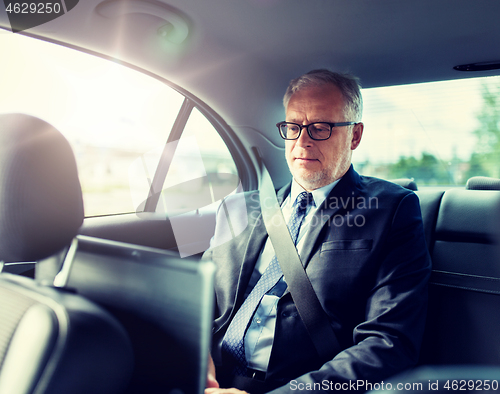 Image of senior businessman driving on car back seat