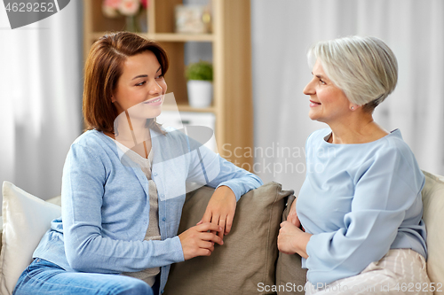 Image of senior mother talking to adult daughter at home