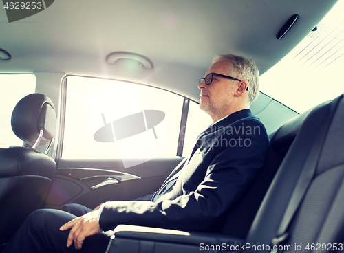 Image of senior businessman driving on car back seat