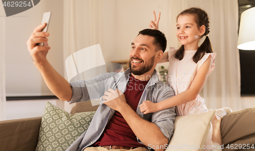 Image of father and daughter taking selfie at home