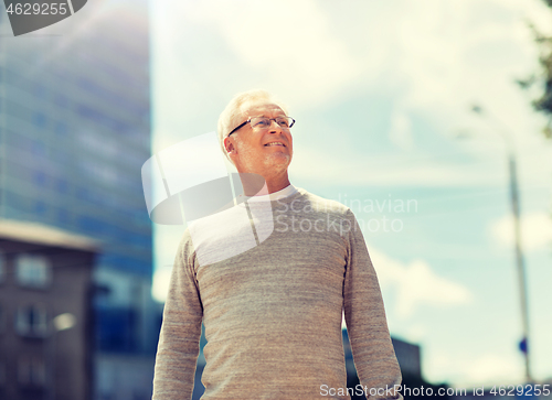 Image of senior man walking along summer city street