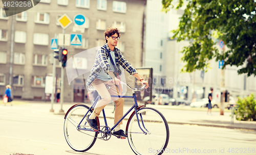 Image of young hipster man with bag riding fixed gear bike