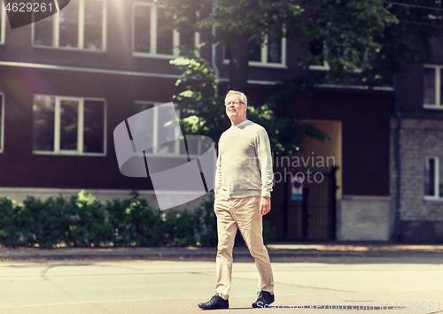 Image of senior man walking along summer city street