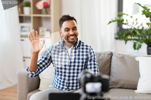 Image of male blogger with camera videoblogging at home