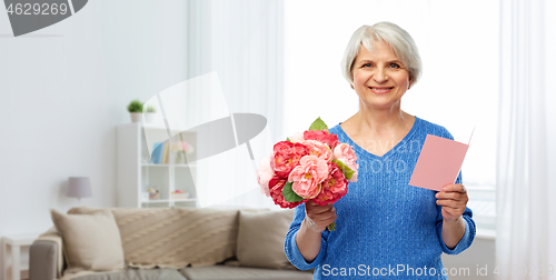 Image of happy senior woman with flowers and greeting card