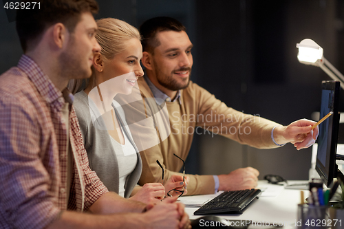 Image of business team with computer working late at office