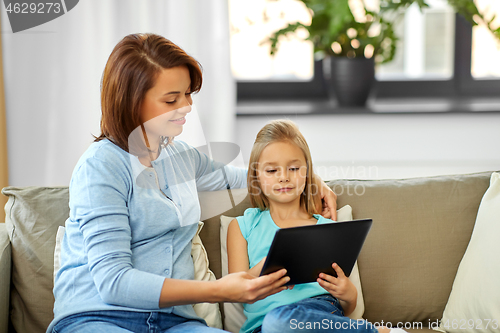 Image of happy mother and daughter with tablet pc at home